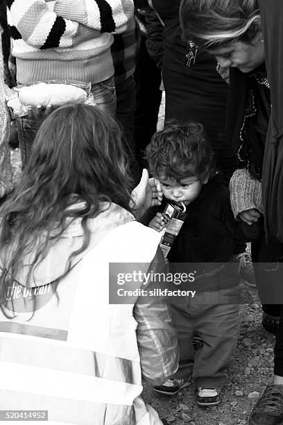volunteer provides food and care for refugee toddler - quiosque stock pictures, royalty-free photos & images