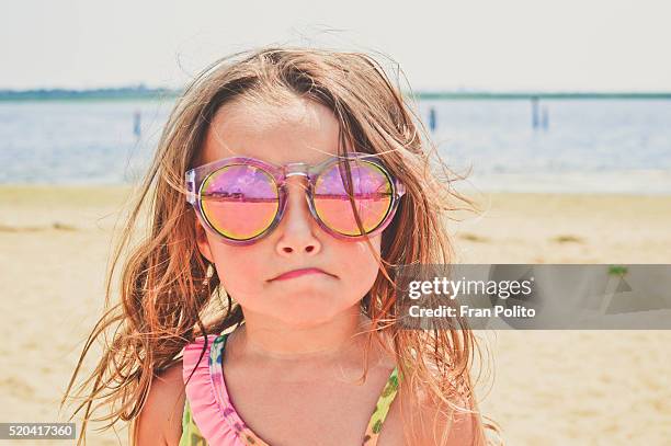 young girl at the beach wearing sunglasses. - water cooler stock-fotos und bilder