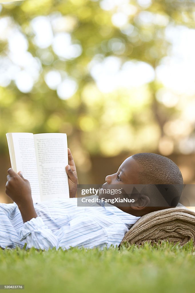 Boy reading outdoors