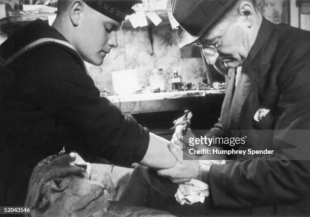 Young sailor in the British navy gets a tattoo on his arm in a Portsmouth tattoo parlour, 19th August 1939. Original Publication : Picture Post - 202...