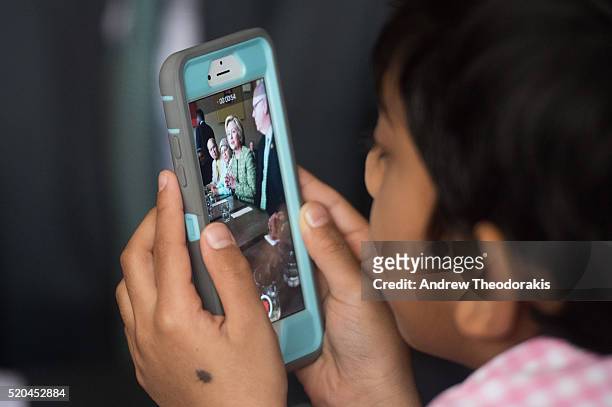 Young boy takes video on his phone of Democratic presidential candidate Hillary Clinton as she visits the Jackson Diner on April 11, 2016 in the...