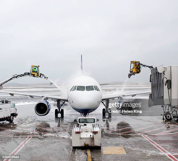 airport workers deicing the wings of an airplane - de ices stock pictures, royalty-free photos & images