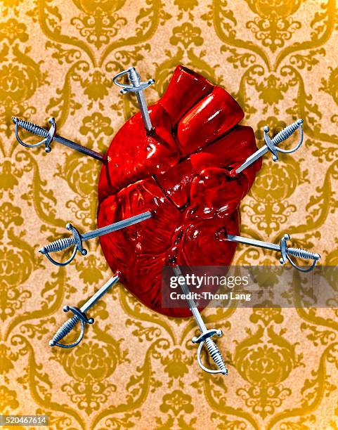 anatomical model of heart stabbed with tiny swords - broken heart stock pictures, royalty-free photos & images