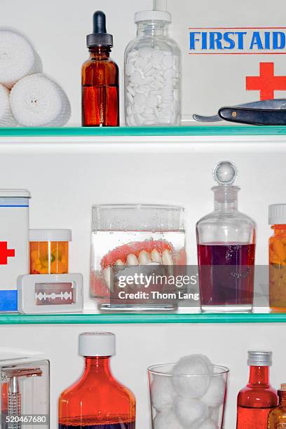 vampire fang dentures in a glass in a mediine cabinet - medicine cabinet stock pictures, royalty-free photos & images