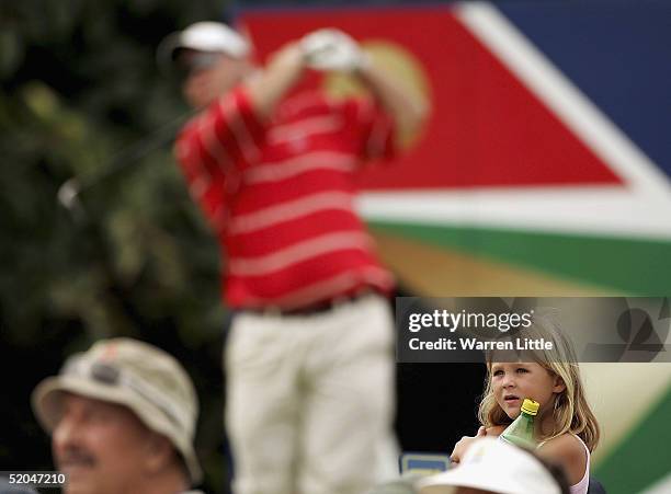 Titch Moore of South Africa tees off on the 18th hole as a little girl from the crowd looks on during the third round of the South African Airways...