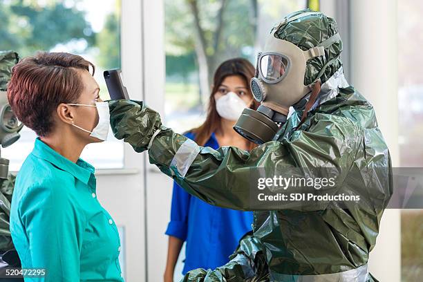 doctor in hazmat suit examining woman during contagious outbreak - ebola stock pictures, royalty-free photos & images