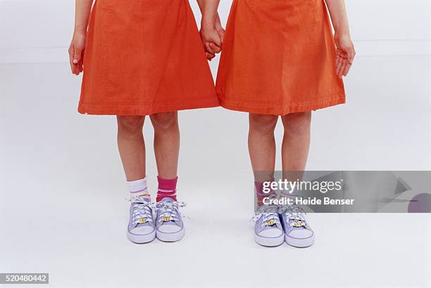 twin sisters holding hands - girls in socks stockfoto's en -beelden