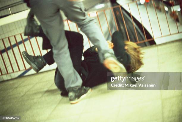 man kicking a woman in subway station - sfida foto e immagini stock