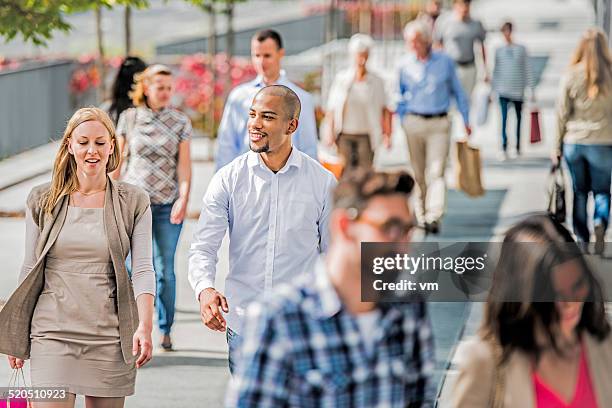 couple on crowded city street after shopping - voetganger stockfoto's en -beelden