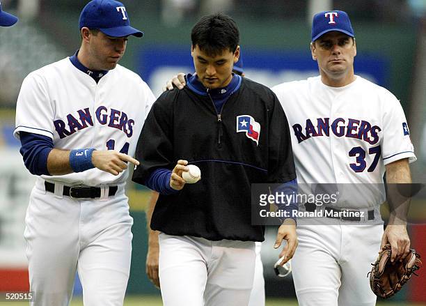 Starting pitcher Chan Ho Park of the Texas Rangers receives the game ball with pitchers Ismael Valdes, left and Kenny Rogers, right after a 5-1 win...