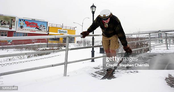 Man wearing shorts and a captain?s hat shovels snow on the Boardwalk January 23, 2005 at Coney Island in the Brooklyn borough of New York City. The...