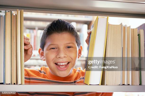 boy smiling between books - gemengde afkomst stockfoto's en -beelden