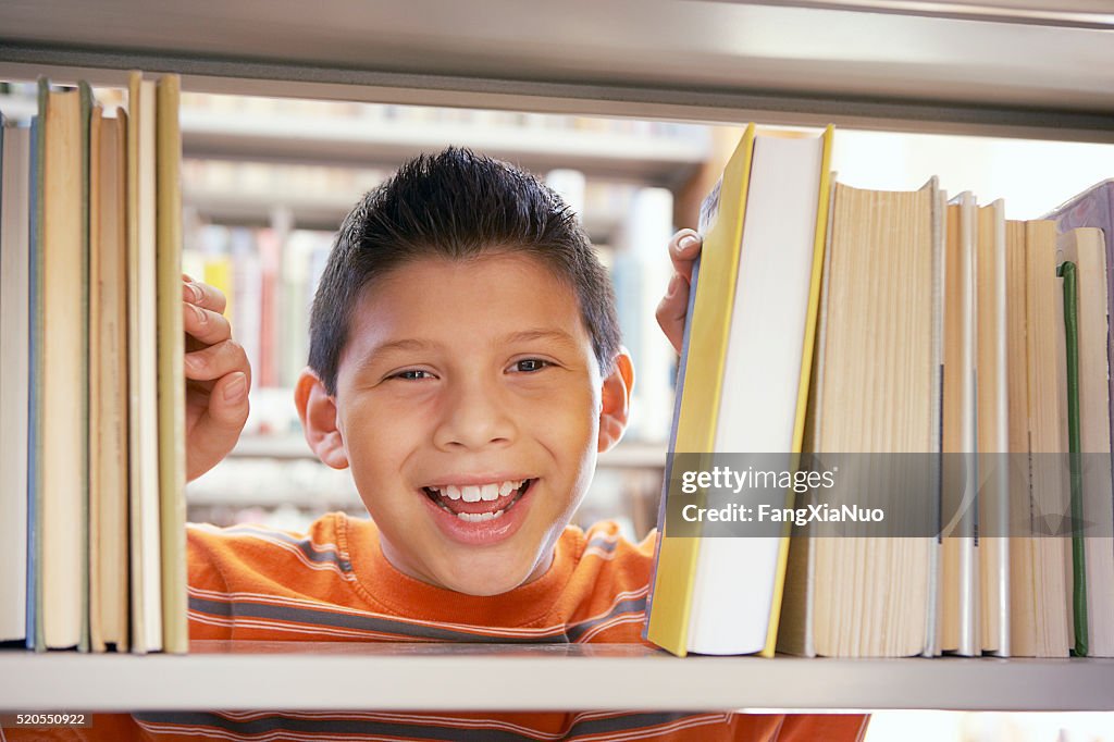 Boy smiling between books