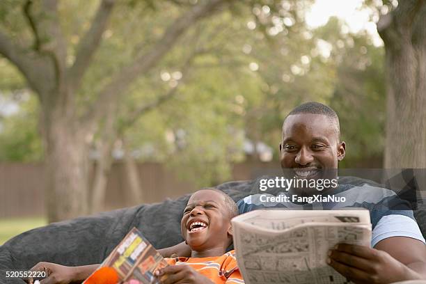 father and son laughing and reading - family time stock pictures, royalty-free photos & images