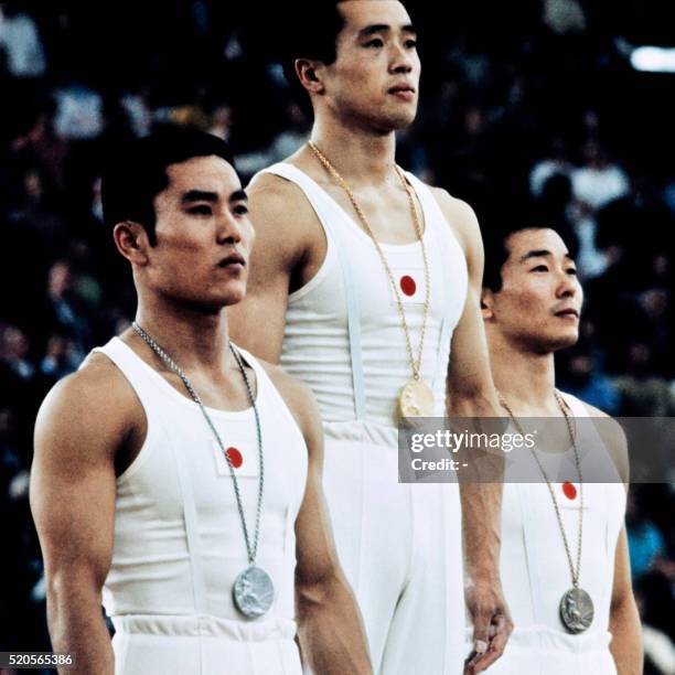 Sawao Kato , gold medallist of the Olympic gymnastics contest stand on the podium in between of Eizo Kenmotsu silver and Akonori Nakayama , bronze,...
