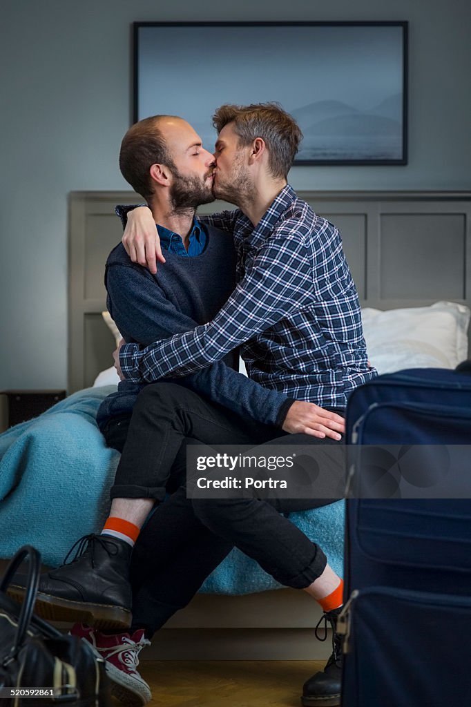 Gay couple kissing in a hotel room