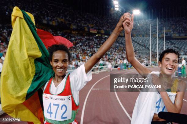 Ethiopia's Derartu Tulu and Elana Meyer of South Africa join hands in a victory lap after the women's 10,000m final at the athletics event during the...