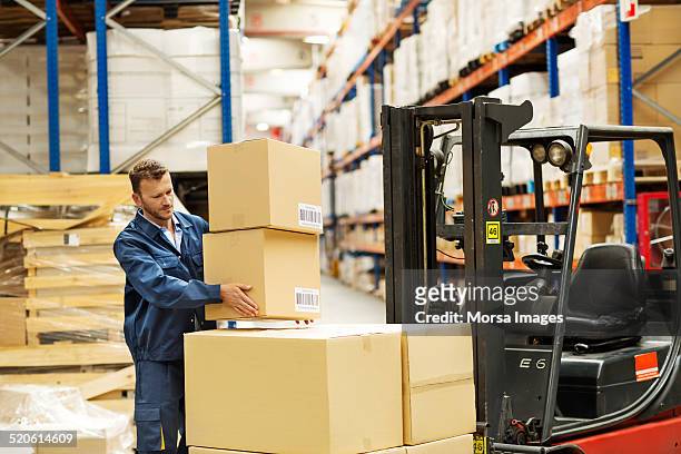 worker loading cardboard boxes on forklift - forklift truck stock pictures, royalty-free photos & images