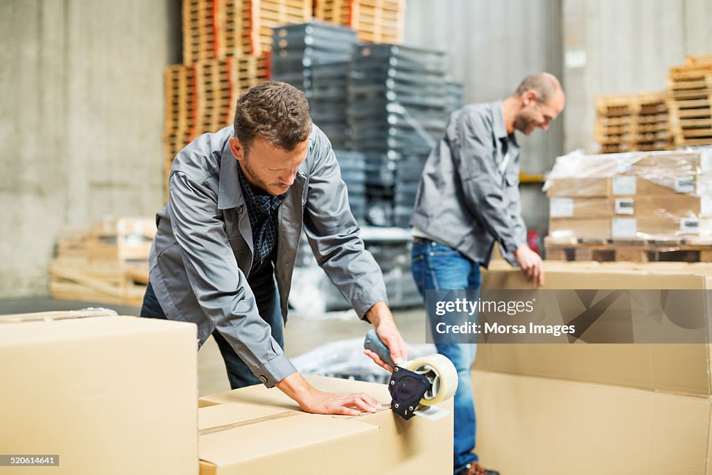 Worker packing cardboard boxes in warehouse