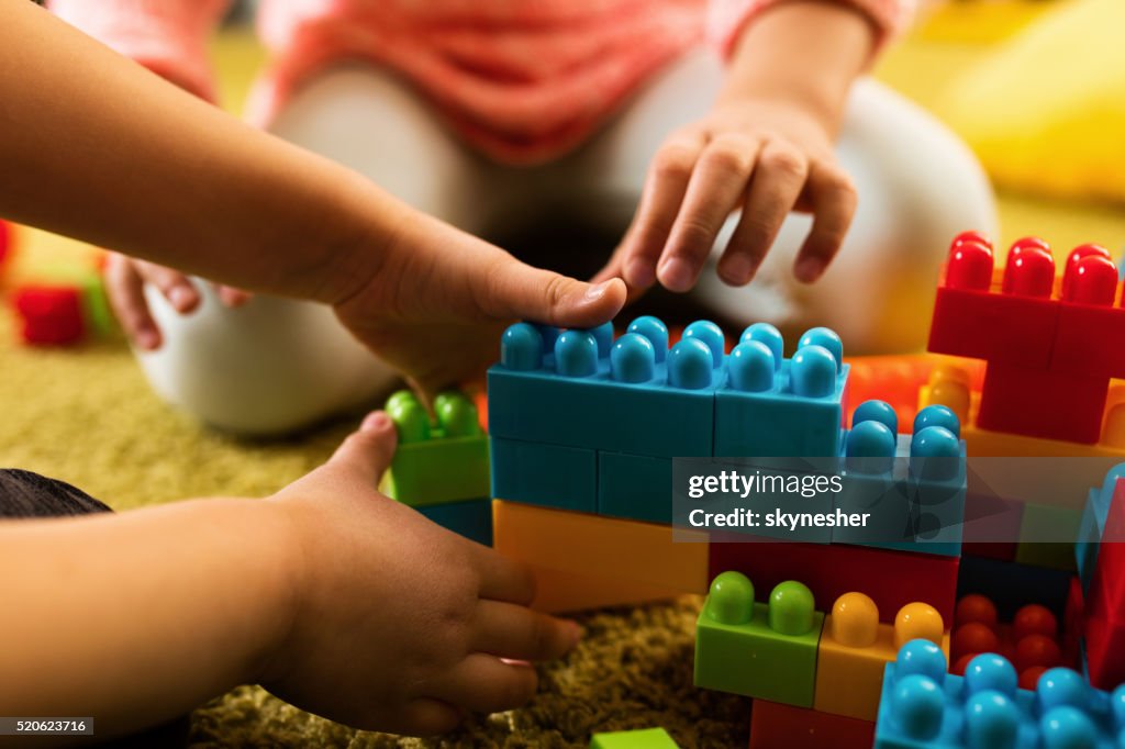 Close-up of two children playing with toy blocks.