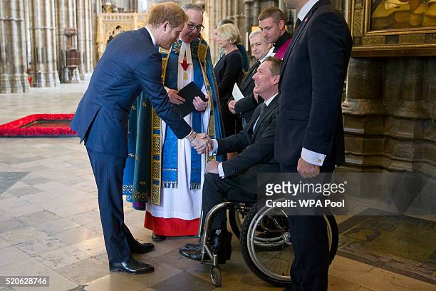 Britain's Prince Harry shakes hands with British journalist Frank Gardner after a service of commemoration for victims of the 2015 terrorist attacks...