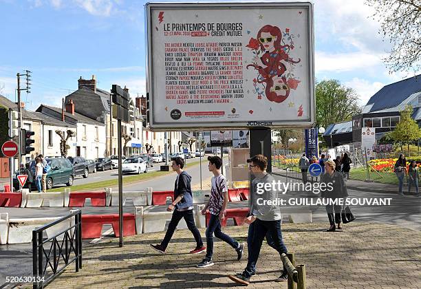 People walk past a billboard advertising the 40th edition of "Le Printemps de Bourges" pop and rock music festival in Bourges on April 12, 2016.