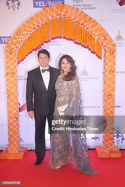 Bollywood actress Madhuri Dixit with her husband Shriram Nene poses for the cameras as they arrive for the Bollywood theme dinner at the Taj Palace...