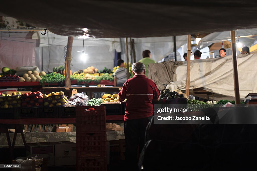 A man in a market stall at night