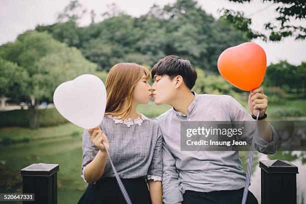 young couple kissing in the park - asian couple kissing stockfoto's en -beelden