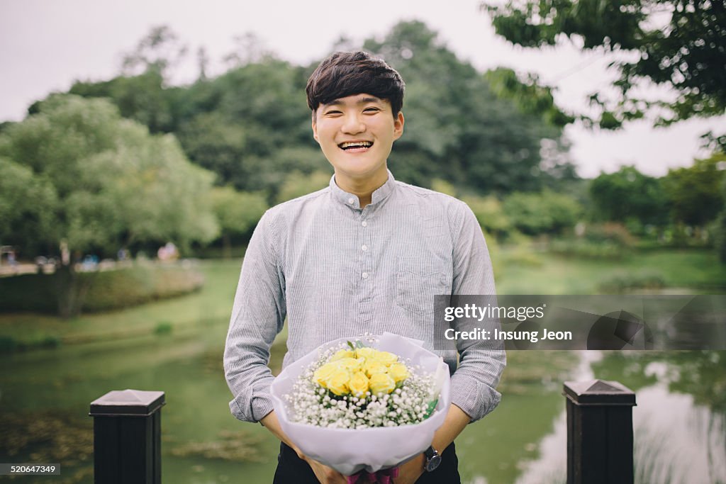 Young man holding yellow flower bouquet