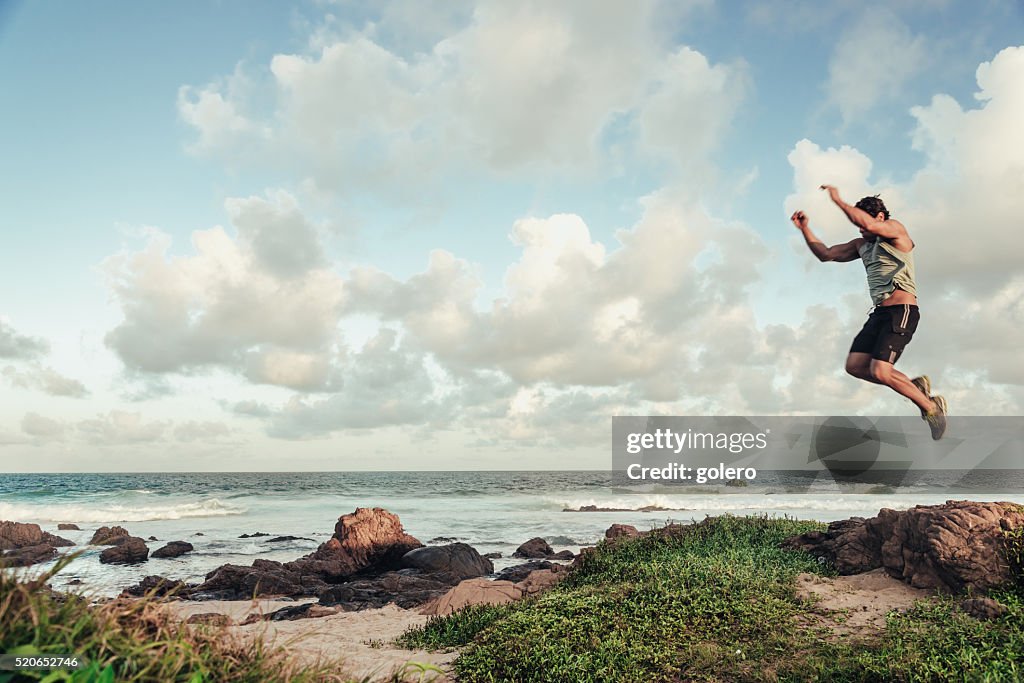 Brasilianische Sportler, die an einem Strand springen im Abendlicht