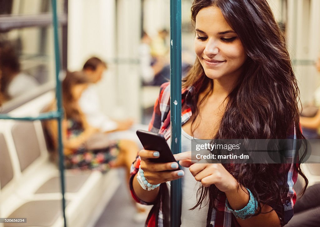 Teenage girl using phone in the subway train