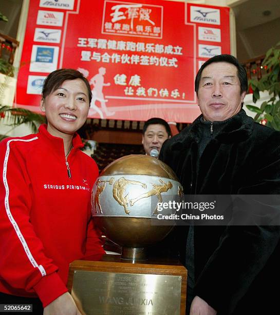 Olympic long-distance running champion Wang Junxia poses for pictures holding an award with her teacher, former China track coach Ma Junren during an...