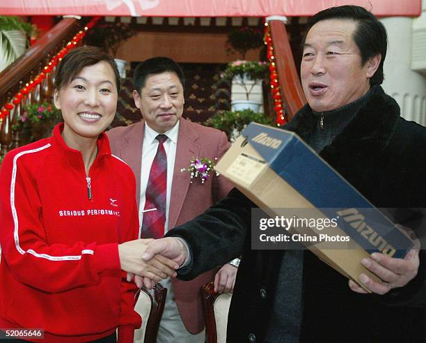 Olympic long-distance running champion Wang Junxia shakes hand with her teacher, former China track coach Ma Junren during an opening ceremony of...