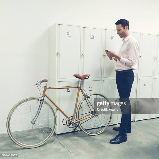 businessman standing near lockers and texting. - locker stock pictures, royalty-free photos & images