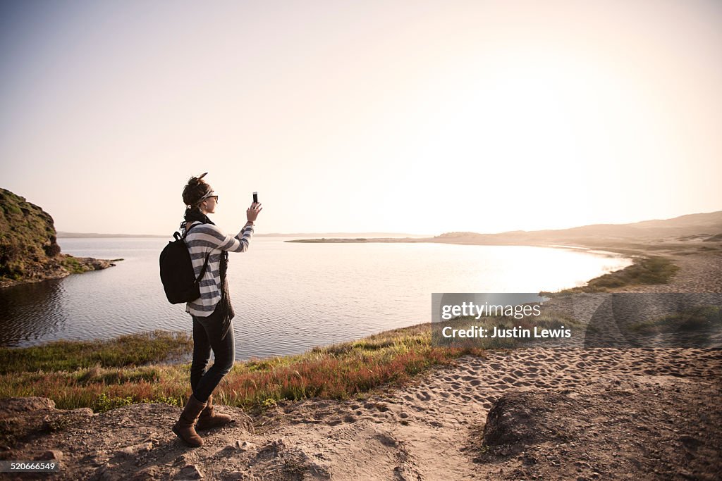 Fashionable young woman takes self-pic at estuary