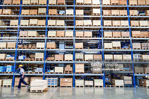 coworker carrying cardboard box in warehouse. - distribution warehouse stockfoto's en -beelden