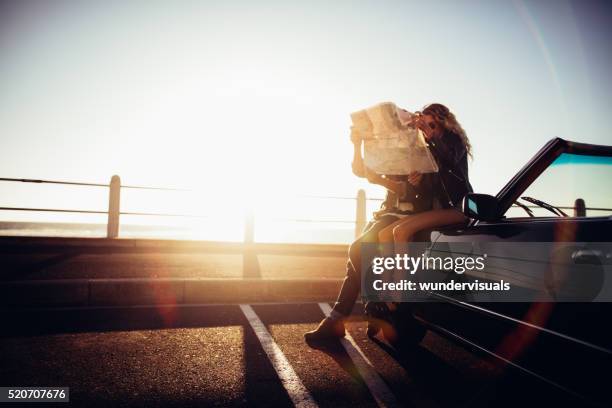 hipster-paar, die ihren sommer am meer autoreise mit fixierbaren ärmeln - girl beach sunset stock-fotos und bilder