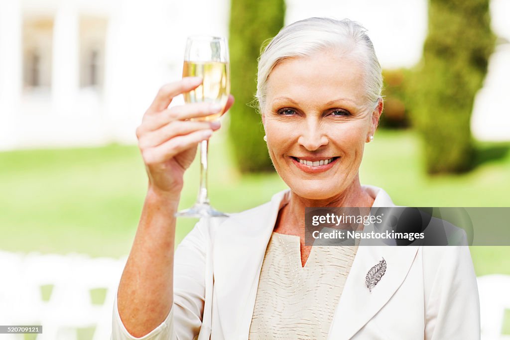 Mulher de tostar Champagne no casamento ao ar livre