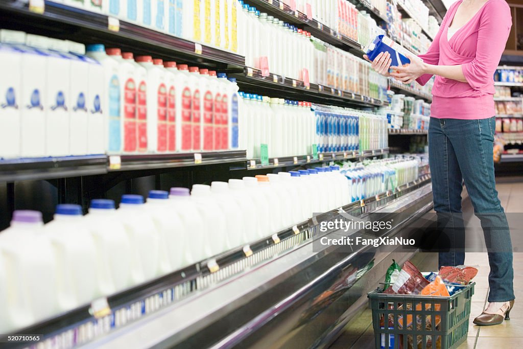 Mid adult woman in supermarket holding milk