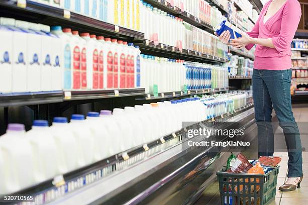 mid adult woman in supermarket holding milk - cartons bildbanksfoton och bilder