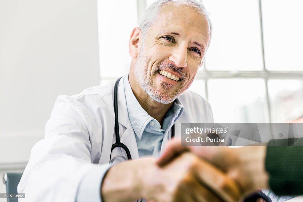 Confident doctor shaking hands with patient