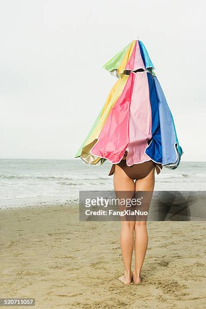 woman covered with beach umbrella standing on beach - beach umbrella isolated stockfoto's en -beelden