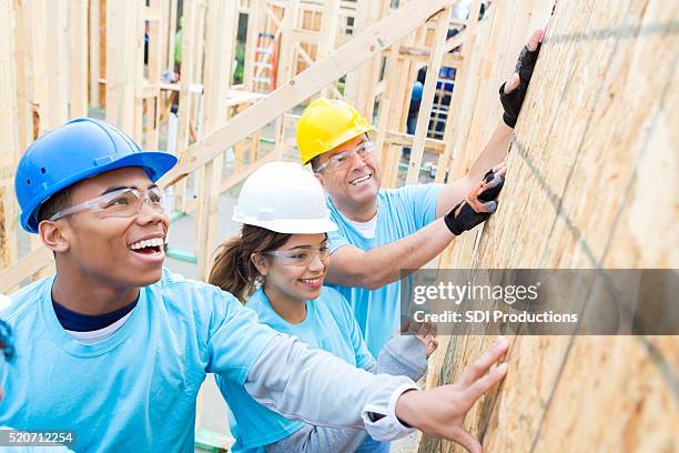 confident volunteers build wall in charity home - happy people holding a white board stock pictures, royalty-free photos & images