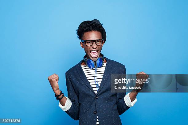fashionable afro american guy expressing happiness - man blue background stockfoto's en -beelden