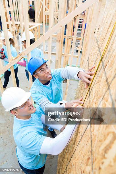 men measure wall in charity home - habitat for humanity stock pictures, royalty-free photos & images