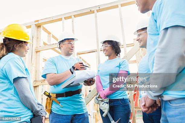 attentive volunteers listen to construction foreman - habitat for humanity stock pictures, royalty-free photos & images