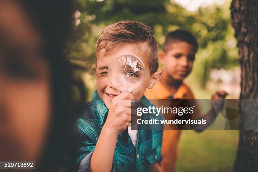 Junge im Park halten Lupe auf seine Augen Junge im Park halten Lupe auf seine Augen