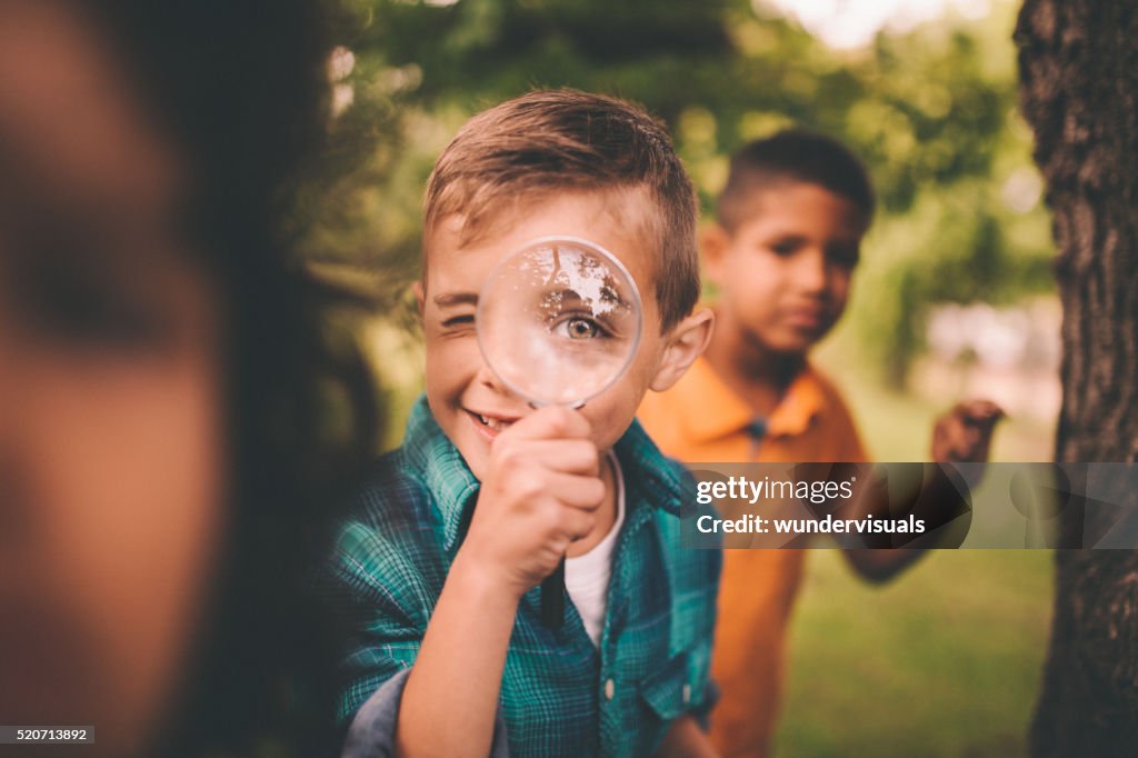 Boy in park holding a magnifying glass to his eye