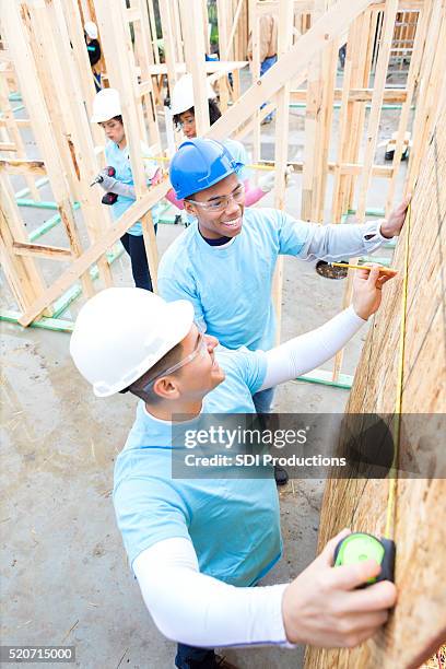 volunteers work together to measure wall at construction site - habitat for humanity stock pictures, royalty-free photos & images
